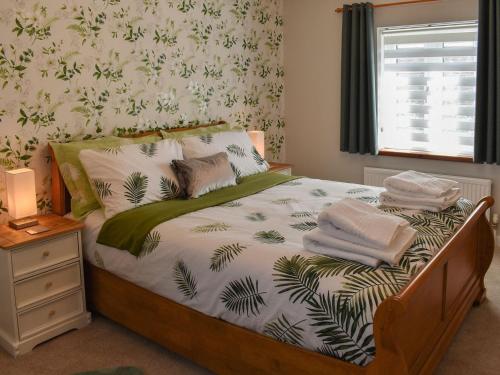 a bedroom with a bed with white sheets and a window at Hawks Mill Cottage in Needham Market