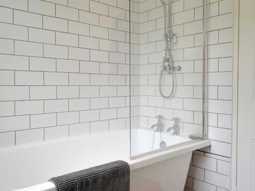 a white tiled shower with a tub and a sink at Brunswick Cottage in Appleby