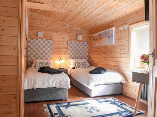 two beds in a room with wooden walls at Astbury Falls Luxury Retreat in Eardington