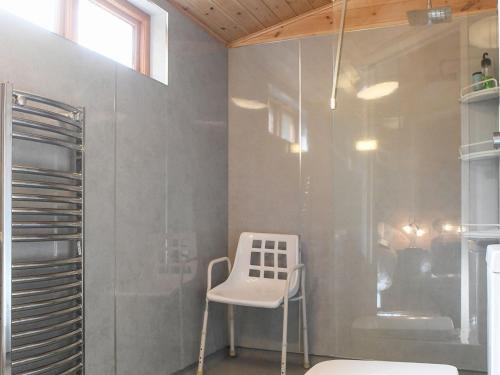 a white chair in a bathroom with a shower at Astbury Falls Luxury Retreat in Eardington