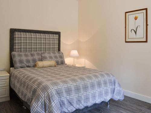 a bedroom with a bed with a plaid blanket at Granary Lodge in binbrook