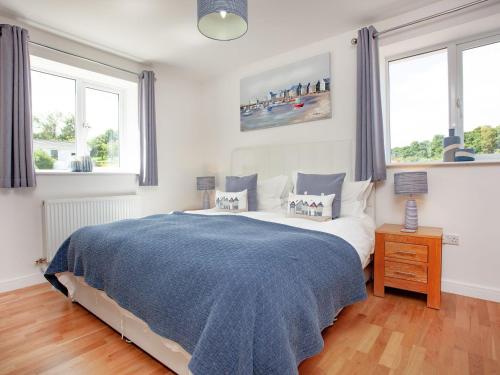 una camera da letto con un letto con una coperta blu e due finestre di Sundance a Cheriton Bishop