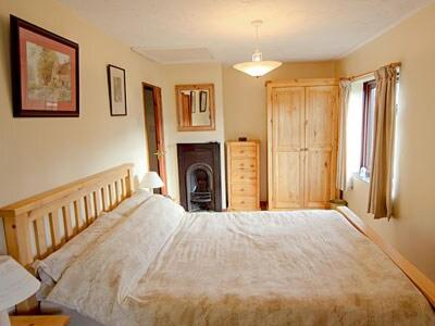 a bedroom with a large bed and a fireplace at Beach Cottage in Winterton-on-Sea