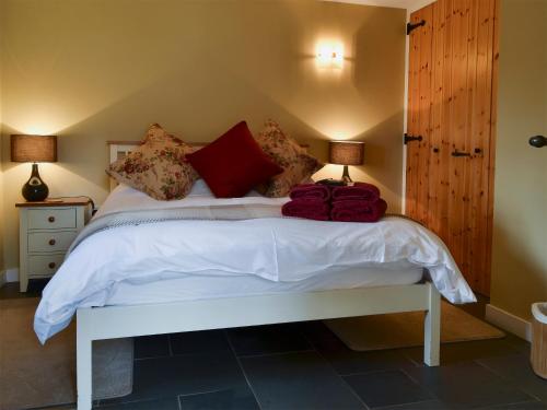 a bedroom with a white bed with red pillows at The Coach House in South Brent