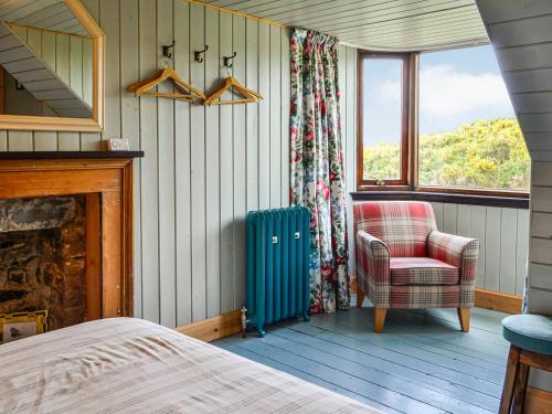 a bedroom with a blue suitcase and a chair at Rosebank Cottage in Borgue