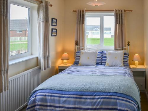 a bedroom with a blue bed with two windows at Rosemarys Sea View in Bacton