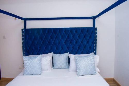 a bed with a blue headboard and white pillows at 2 B/room Nyali City Mall W/Pool in Mombasa