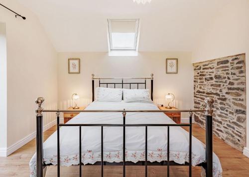 a bedroom with a bed and a brick wall at Sgubor Fach in Pen-y-bont-fawr
