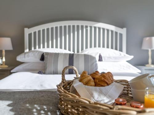 a basket of bread and orange juice on a bed at Cow Pasture Cottage in Hallington