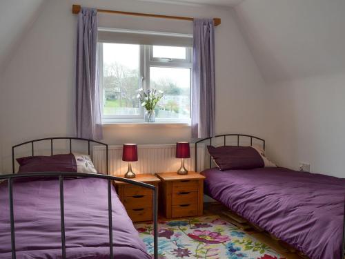 2 camas individuales en una habitación con ventana en Sea Breezes, en Totland