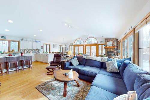 a living room with a blue couch and a kitchen at Ski Bike the East in Stowe