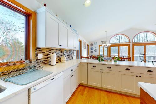 a kitchen with white cabinets and a large window at Ski Bike the East in Stowe