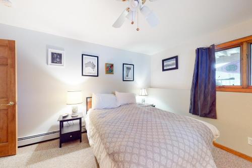 a white bedroom with a bed and a window at Ski Bike the East in Stowe