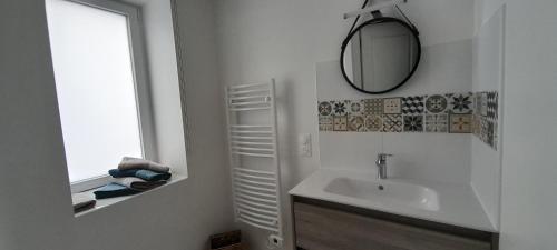ein weißes Badezimmer mit einem Waschbecken und einem Spiegel in der Unterkunft Le Gîte de la fontaine in Neuvy-le-Roi