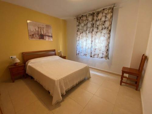 1 dormitorio con cama y ventana con cortina en Sirocco Apartamento, en Oropesa del Mar