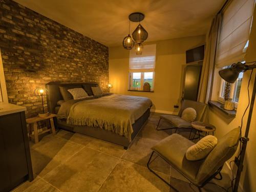 een slaapkamer met een bed en een bakstenen muur bij Gastenverblijf Bie Zus in Buggenum