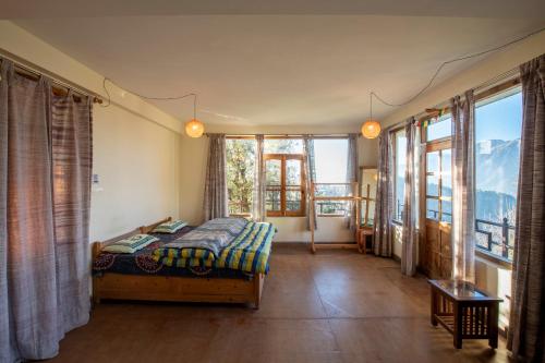 a bedroom with a bed in a room with windows at Naddi Castle in McLeod Ganj
