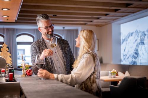 a man and a woman standing at a bar drinking wine at Naturhotel Tandler in Sankt Jakob in Defereggen
