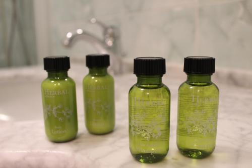 three green bottles sitting on a bathroom counter at Hotel Belle Epoque in Sanremo