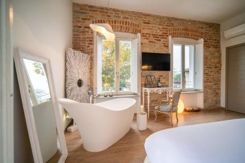 a bathroom with a white tub and a brick wall at Langhe Country House in Neive