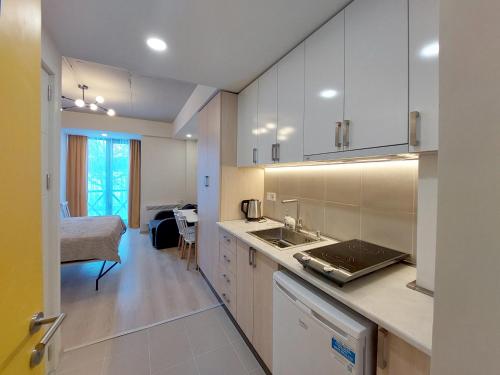 una cocina con armarios blancos y una cama en una habitación en Bakuriani Mix Apartment 207, en Bakuriani