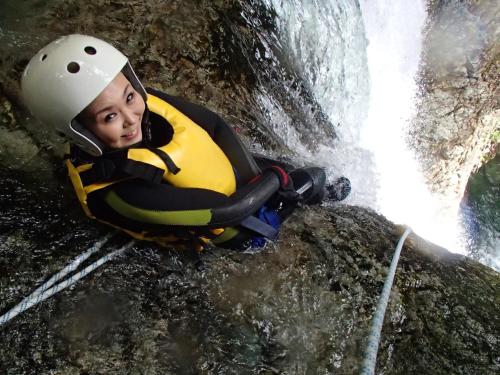 a woman in a helmet climbing a waterfall at Zazan minakami in Minakami