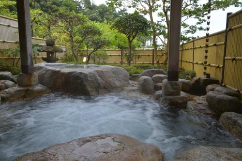 a stream in a garden with rocks and a fountain at Shikanoyu Hotel in Komono