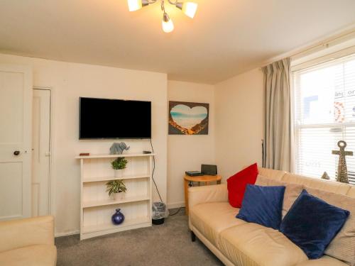 a living room with a couch and a flat screen tv at Lobster Cottage in Weymouth