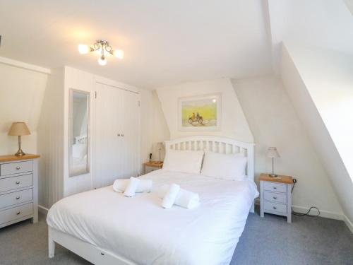 a bedroom with a white bed with white pillows at Lobster Cottage in Weymouth