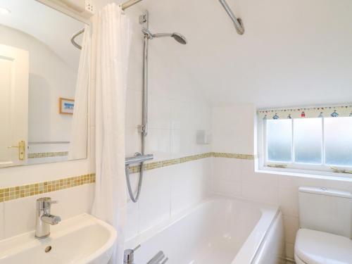 韋茅斯的住宿－Lobster Cottage，白色的浴室设有浴缸和水槽。