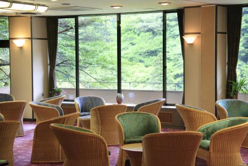a room with chairs and tables and large windows at Shikanoyu Hotel in Komono