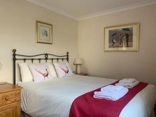 um quarto com uma cama grande e toalhas em Nursery Cottage em North Somercotes