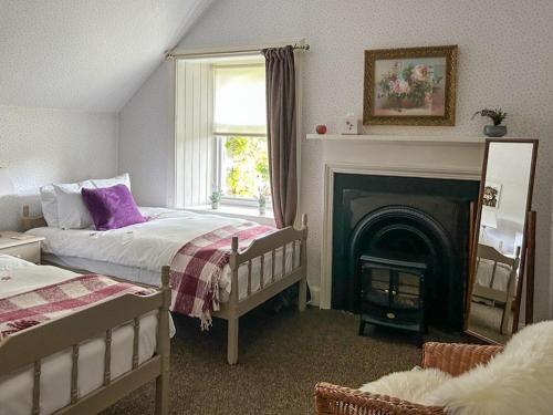 1 dormitorio con 2 camas y chimenea en Creag Darach Cottage en Aberfoyle