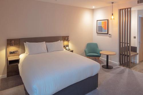 a bedroom with a large bed and a green chair at Holiday Inn Sunderland - City Centre, an IHG Hotel in Sunderland