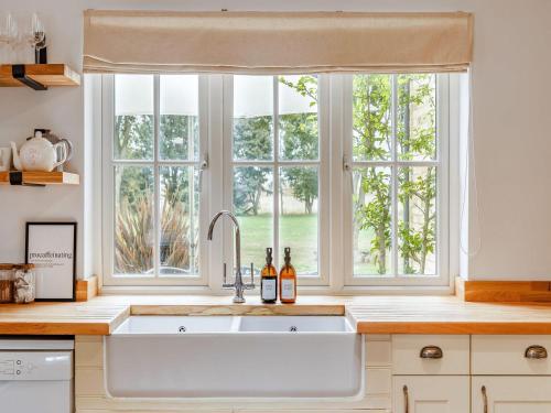 a kitchen with a sink and three windows at Chittering Farm in Stretham