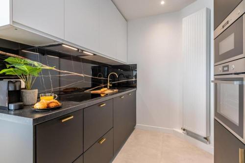 une cuisine avec des placards gris et un comptoir noir dans l'établissement Sweett - Pont Neuf, à Paris