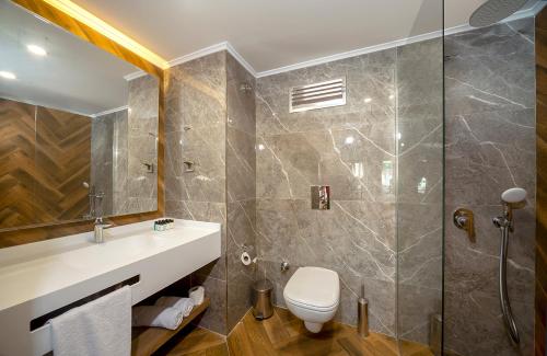 Un baño con inodoro, lavabo y ducha. en LUCAS DIDIM RESORT, en Yenihisar