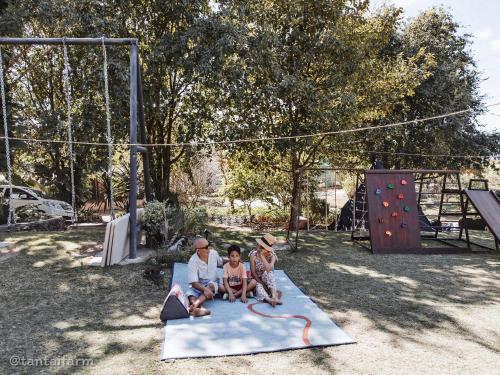 a man and two children sitting on a play mat at Tantai Eco Farm Stay At Khao Yai in Ban Sap Noi