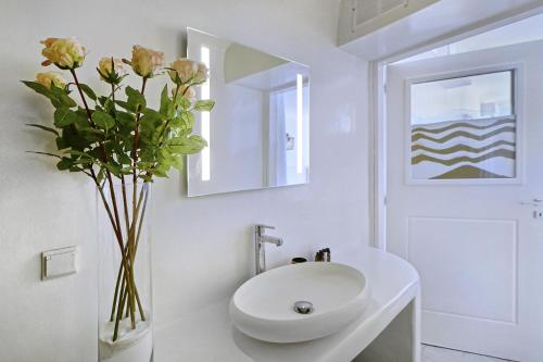 baño con lavabo blanco y jarrón con flores en Zinas Villas, en Fanari
