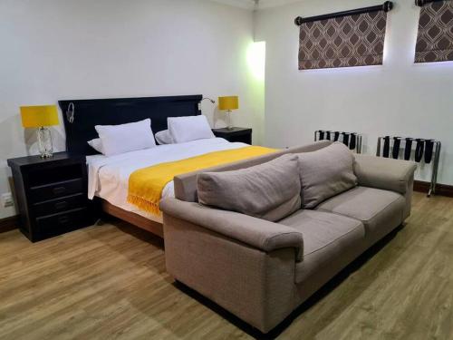 ein Schlafzimmer mit einem Bett, einem Sofa und einem Bett in der Unterkunft Spacious Golf & Wildlife Estate in Hartbeespoort 10 sleeper in Hartbeespoort