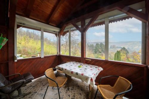 a table and chairs in a room with windows at Holiday home Nanin konak 2 in Vrdnik
