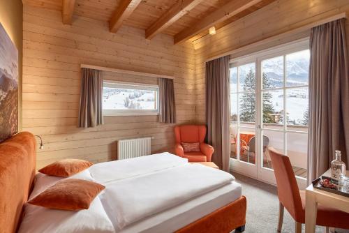 ein Schlafzimmer mit einem Bett, einem Stuhl und einem Fenster in der Unterkunft Dolomit Boutique Hotel in Stern