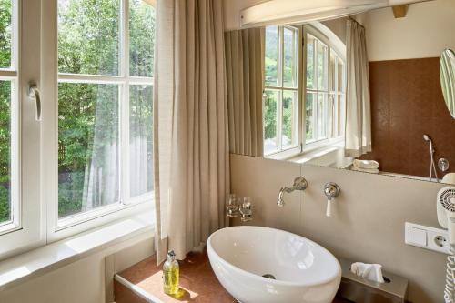 a bathroom with a sink and a mirror and windows at Dolomit Boutique Hotel in La Villa