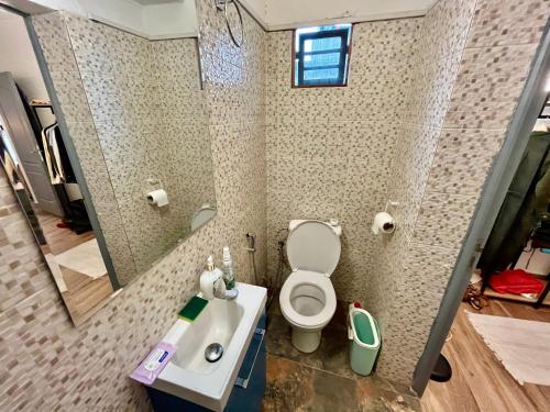 La salle de bains est pourvue de toilettes, d'un lavabo et d'un miroir. dans l'établissement Dakar cosy maison avec terrasse by immo kit bnb, à Dakar