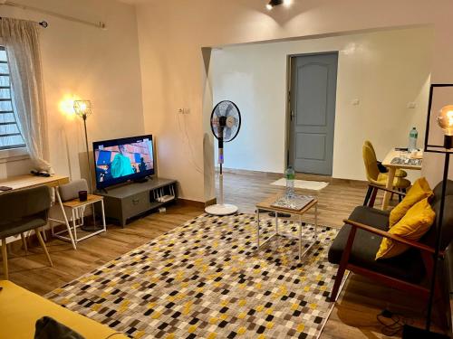 sala de estar con TV, sofá y mesa en Dakar cosy maison avec terrasse by immo kit bnb, en Dakar