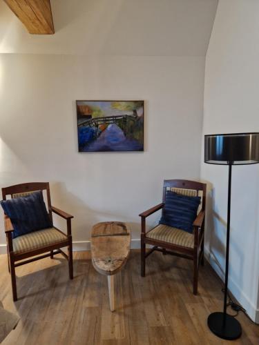 two chairs and a table in a room with a painting at De WiedenWeide in Wanneperveen