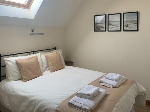 a bedroom with a white bed with towels on it at Mill House in North Somercotes