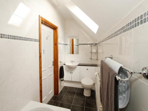 a white bathroom with a toilet and a sink at Mill House in North Somercotes