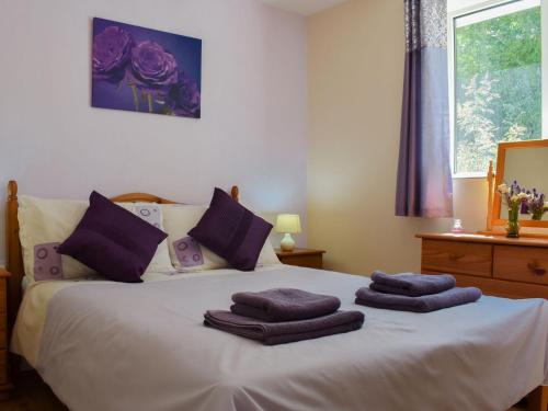 a bedroom with a bed with purple towels on it at Green Valley Retreat in Holsworthy