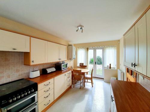 a kitchen with white cabinets and a table in it at Red Lion Cottage in Chatteris
